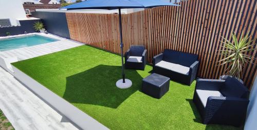 a patio with chairs and an umbrella and a pool at Azure Sunset in Ponta Delgada