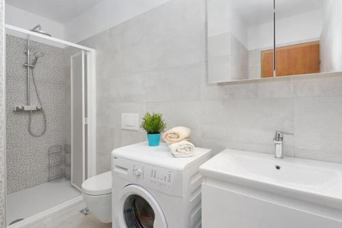 biała łazienka z pralką i umywalką w obiekcie Apartments Emilia w Rabacu