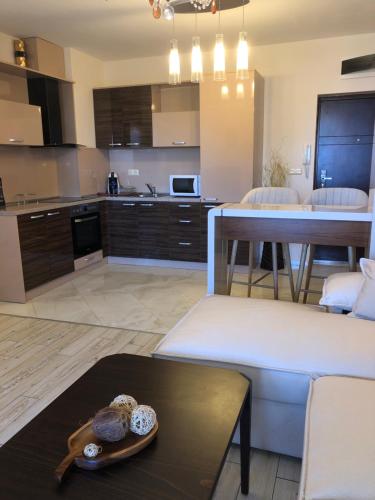 a living room with a couch and a table and a kitchen at Апартамент VESI комплекс ARTUR in Sveti Vlas