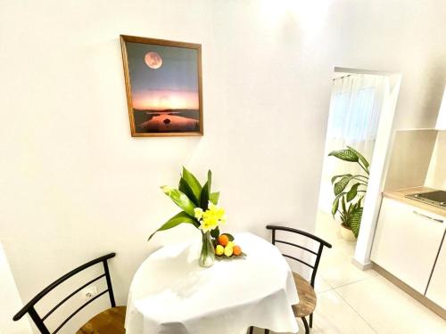 a white table with a vase of flowers on it at Morska in Orebić