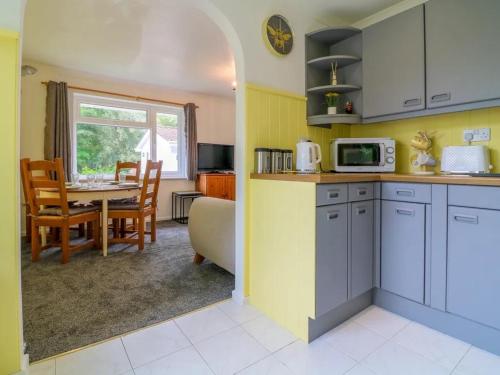 a kitchen and dining room with a table and a microwave at Beekeepers Cottage in Liskeard