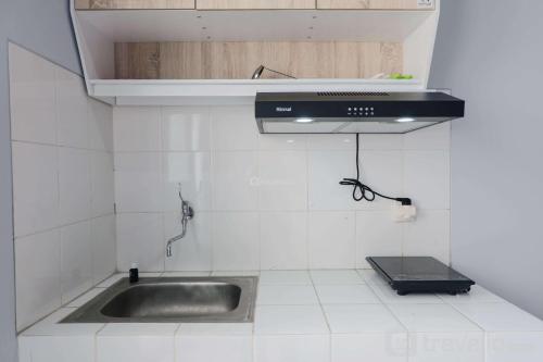a kitchen with a sink and a stove at Homey 1BR Apartment at Newton Residence Bandung By Travelio in Bandung