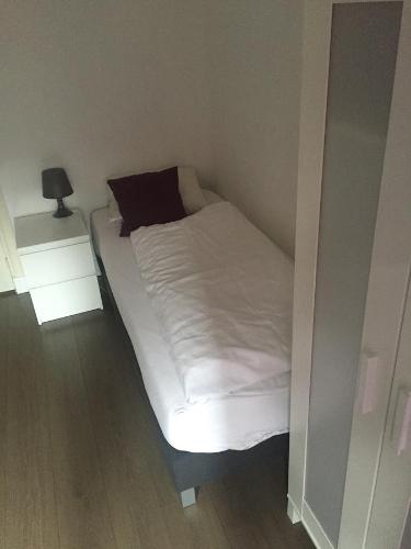a small bedroom with a bed with white sheets at Hotel Bij Verhoeven in Zevenbergen