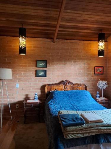 a bedroom with a bed and a brick wall at CASA EM MONTE VERDE CHARME E CONFORTO in Monte Verde