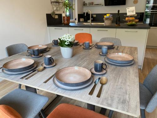 a wooden table with plates and utensils on it at Waldblick - Holiday home with wellness in Ouren in Burg-Reuland