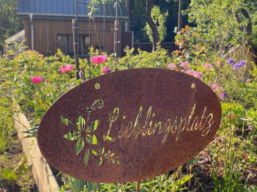 a sign in the middle of a garden with flowers at Waldblick - Holiday home with wellness in Ouren in Burg-Reuland