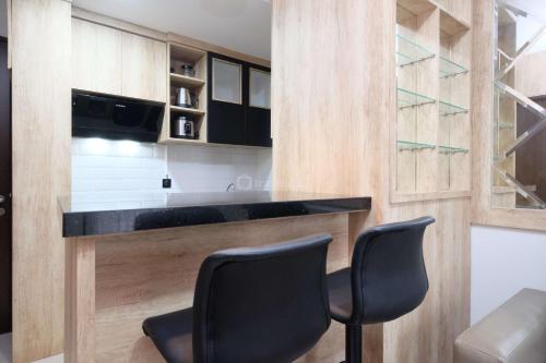 a kitchen with a black counter and two chairs at Modern Look and Comfy 2BR Transpark Cibubur Apartment By Travelio in Depok
