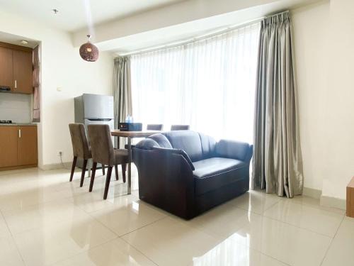 a living room with a blue couch and a table at Modern Look 2BR at Grand Kamala Lagoon Apartment By Travelio in Bekasi