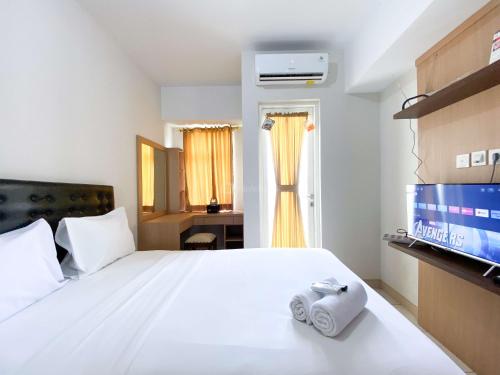 ein Schlafzimmer mit einem weißen Bett und einem Fernseher in der Unterkunft Great Deal Studio at Springlake Summarecon Bekasi Apartment By Travelio in Bekasi