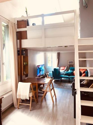 Cette chambre comprend une mezzanine avec une table et un canapé. dans l'établissement Little Normandie, à Saint-Ouen