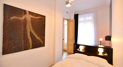 ein Schlafzimmer mit einem Gemälde an der Wand und einem Bett in der Unterkunft Appart' Pasteur in Lyon
