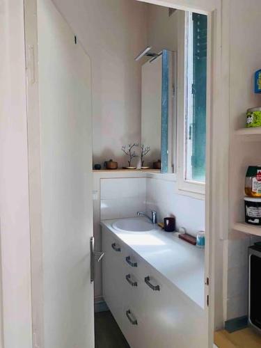 une salle de bain blanche avec un lavabo et une fenêtre dans l'établissement Little Normandie, à Saint-Ouen