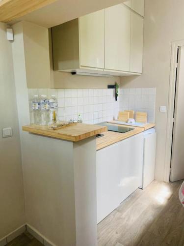 une cuisine avec des armoires blanches et un comptoir en bois dans l'établissement Little Normandie, à Saint-Ouen