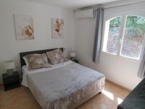 une chambre avec un grand lit avec deux fenêtres dans l'établissement Le Vendémiaire, à Cassis