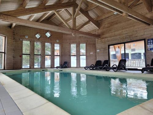 a large swimming pool with chairs in a building at Chalet By Sophie Superdevoluy avec piscine in Superdevoluy