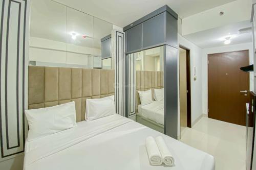 a bedroom with a large white bed and a mirror at Comfy and Tidy Studio Transpark Cibubur Apartment By Travelio in Depok