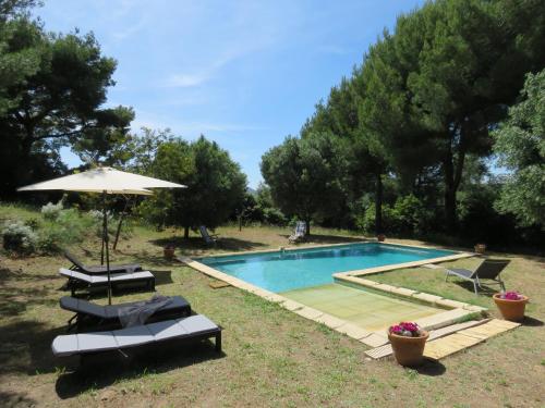 une piscine avec deux chaises et un parasol dans l'établissement Le Vendémiaire, à Cassis