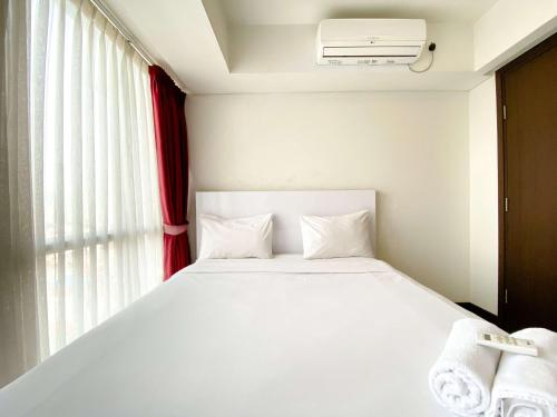 a white bed in a room with a window at Comfort Stay and Homey 2BR Apartment at H Residence By Travelio in Jakarta