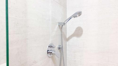 a shower with a shower head in a bathroom at Minimalist and Nice Studio at Gold Coast Apartment By Travelio in Jakarta