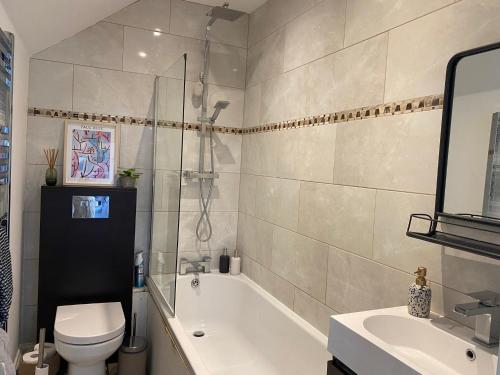 a bathroom with a tub and a toilet and a sink at Charming Edwardian maisonette in trendy location, minutes from restaurants and pubs in Ashley Cross, Poole in Poole