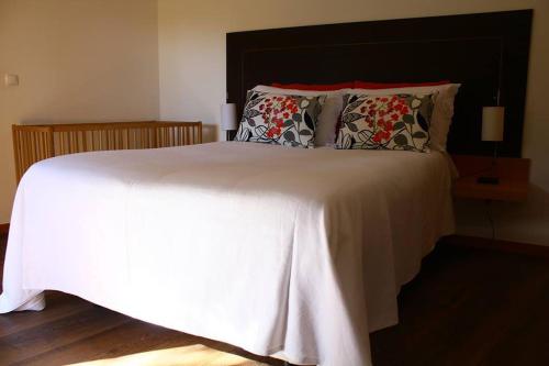 a bedroom with a large white bed with pillows at As Casinhas de Loureda in Arcos de Valdevez