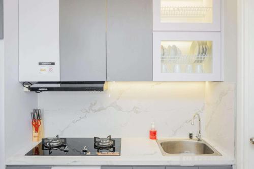 a white kitchen with a sink and a stove at Luxurious and Spacious Apartment 2BR Tuscany Residence BSD By Travelio in Ciater-tengah