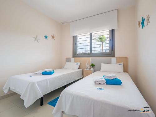 2 Betten in einem Zimmer mit weißen Wänden und einem Fenster in der Unterkunft Apartment Perla del Sol in Arenales del Sol