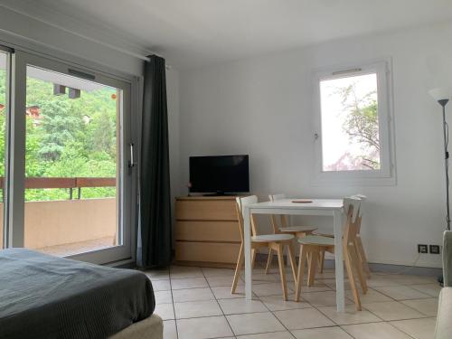 une chambre avec un lit, une table et une télévision dans l'établissement Studio au cœur de Brides-les-Bains face au parc thermal, balcon, parking, idéal pour curistes et skieurs - FR-1-512-126, à Brides-les-Bains