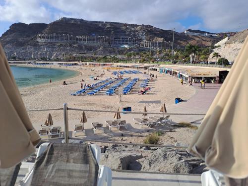 a beach with chairs and umbrellas and the ocean at Incredible Sunsets in Puerto Rico de Gran Canaria