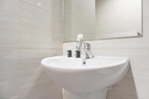 a white bathroom with a sink and a mirror at Best Homey and Nice 2BR at Ciputra International Apartment By Travelio in Jakarta