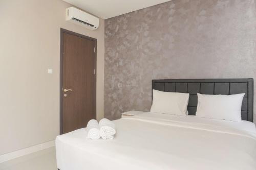 a bedroom with a bed with white sheets and white shoes at Best Homey and Nice 2BR at Ciputra International Apartment By Travelio in Jakarta