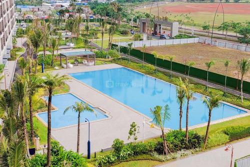 eine Draufsicht auf einen Swimmingpool mit Palmen in der Unterkunft Great Choice and Homey Studio Room Sky House BSD Apartment By Travelio in Tangerang