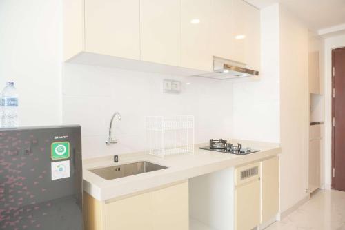 a white kitchen with a sink and a counter at Comfy Stay Studio at Sky House BSD Apartment By Travelio in Tangerang