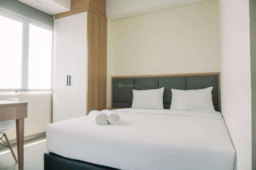 a bedroom with a large white bed with two towels on it at Strategic and Best Deal Studio at Apartment B Residence By Travelio in Tangerang