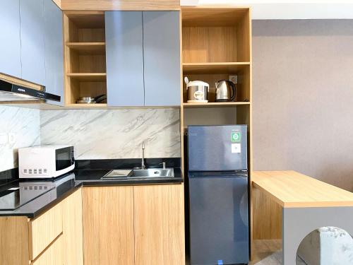 a kitchen with a refrigerator and a microwave at Homey and Spacious Studio Vasanta Innopark Apartment By Travelio in Cikarang