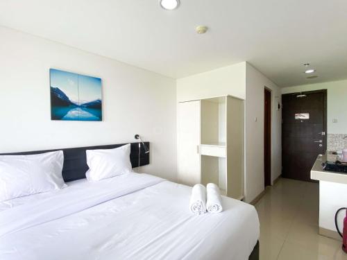 a bedroom with a bed with two white slippers on it at Enjoy Living Studio at Enviro Apartment By Travelio in Cikarang