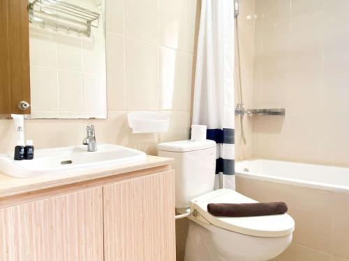 a bathroom with a toilet and a sink and a tub at Best Deal and Comfortable 2BR Oasis Cikarang Apartment By Travelio in Cikarang