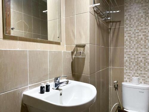 a bathroom with a sink and a mirror and a toilet at Enjoy Living Studio at Enviro Apartment By Travelio in Cikarang