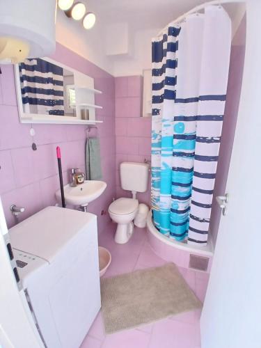 różowa łazienka z toaletą i umywalką w obiekcie Apartments Neo w mieście Rukavac