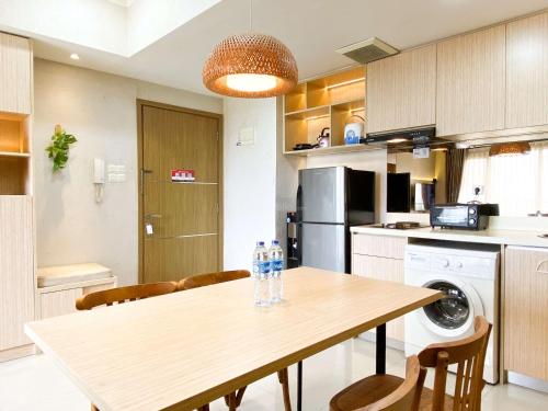 a kitchen with a table with chairs and a washer at Best Deal and Comfortable 2BR Oasis Cikarang Apartment By Travelio in Cikarang