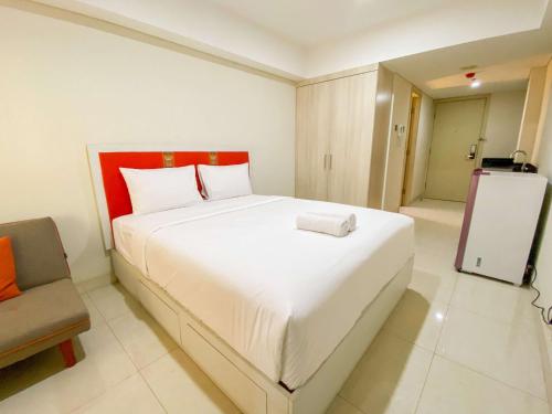 a bedroom with a large white bed and a chair at Good Deal Studio Apartment at Warhol (W/R) Residences By Travelio in Semarang