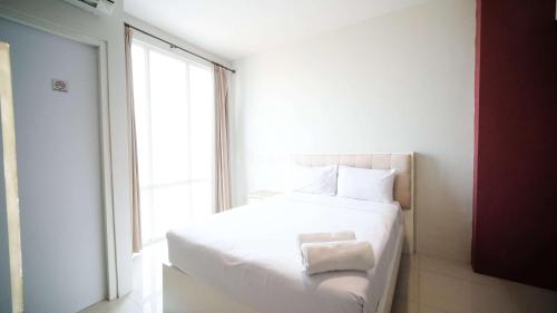a white bed in a room with a window at Best Choice and Homey Studio at The Square Surabaya Apartment By Travelio in Surabaya
