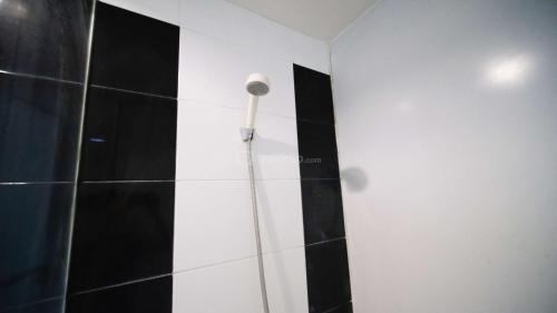 a shower in a bathroom with black and white tile at Best Choice and Homey Studio at The Square Surabaya Apartment By Travelio in Surabaya