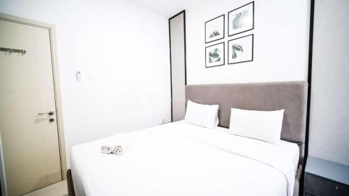 a bedroom with a large white bed with two pillows at Comfortable Living 2BR at Anderson Supermall Mansion Apartment By Travelio in Surabaya