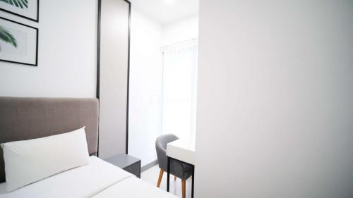 a bedroom with a bed and a desk and a window at Comfortable Living 2BR at Anderson Supermall Mansion Apartment By Travelio in Surabaya