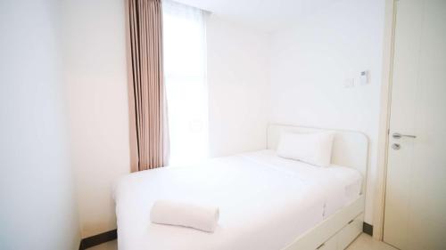 a white bed in a room with a window at Comfortable Living 2BR at Anderson Supermall Mansion Apartment By Travelio in Surabaya
