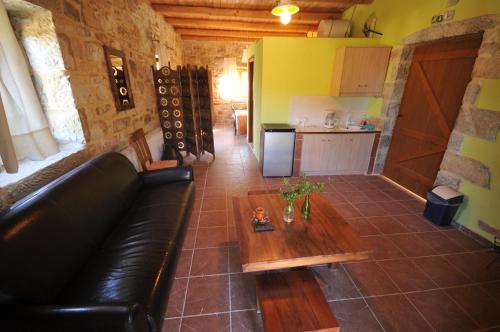 a living room with a black leather couch and a table at Akros Oreon, Omalos Studio in Káto Sími