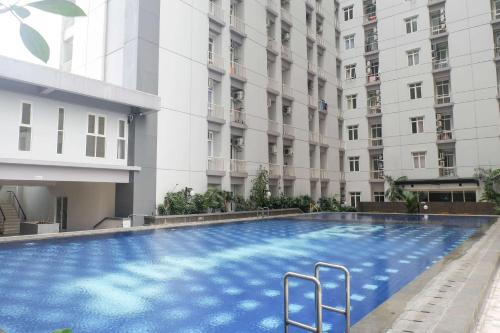 a large swimming pool in front of a building at Best Choice and Cozy Living 2BR at Bale Hinggil Apartment By Travelio in Medokanayu