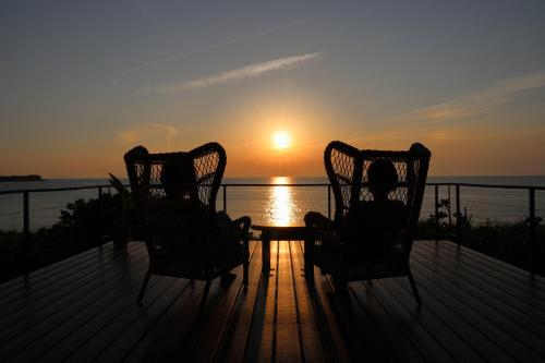 two people sitting in chairs on a deck watching the sunset at The Gold Beach House in Daisen