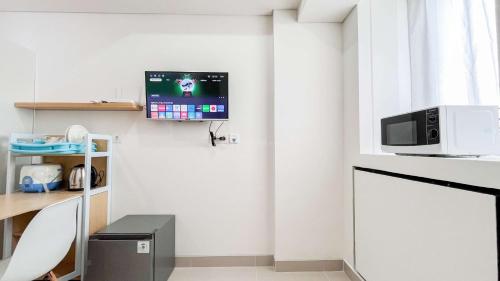 a living room with a tv on the wall at Tranquil Studio (No Kitchen) Apartment Bandaraya - Tallasa City Makassar By Travelio in Pacinongong